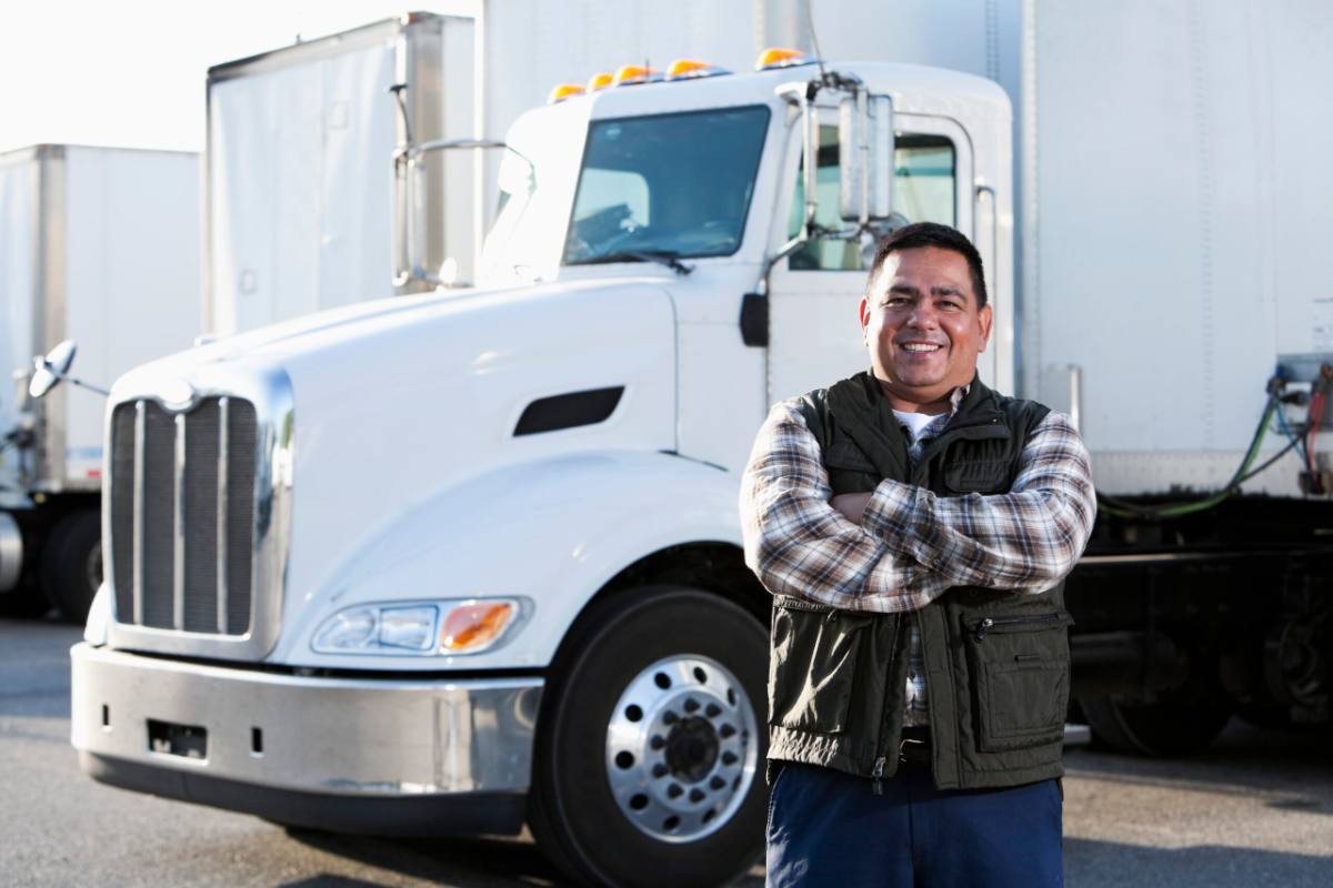 Truck driver experiencing back pain while driving truck Owner-operator standing in front of his commercial truck